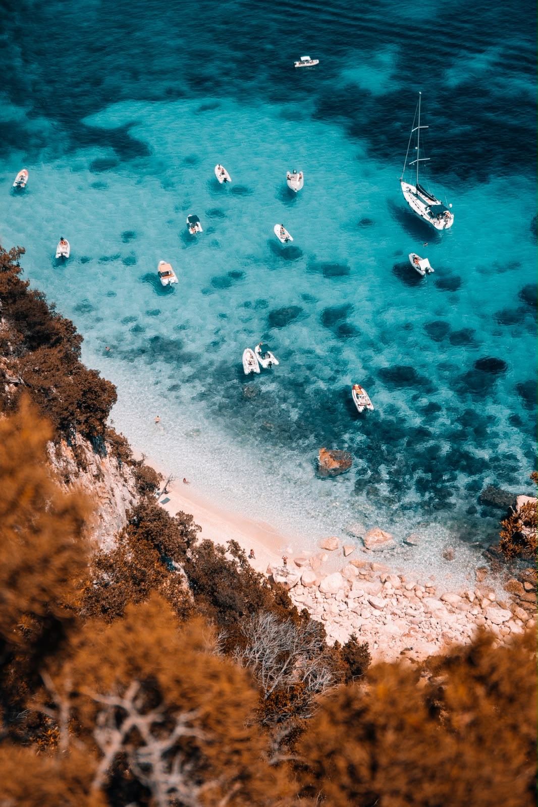 Gommoni e una barca a vela nell’acqua turchese di una cala del Golfo di Orosei